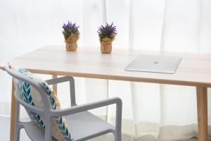 een tafel met een laptop en een stoel met bloemen bij Apartamentos La Gringa Centro Gijon I Obra nueva con posibilidad de Parking in Gijón