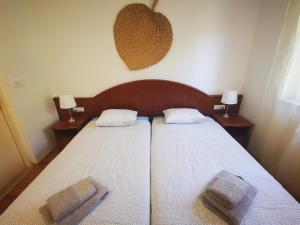 a bedroom with two beds with white sheets and two lamps at Airport Garden Apartments in Čilipi