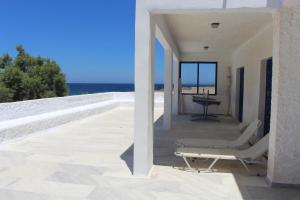 Un balcón con una silla y vistas al océano. en Villa Akrotiri – The Star Watcher en Engares