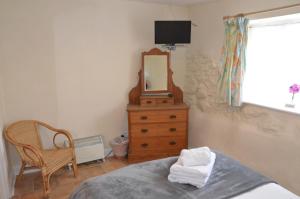a bedroom with a bed and a mirror and a chair at The Royal Oak Inn in Dunsford
