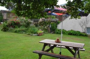 a wooden picnic table with an umbrella on a yard at The Royal Oak Inn in Dunsford