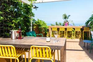 a wooden table with yellow chairs and wine bottles on a patio at Hotel Beit Maimon in Zikhron Ya'akov