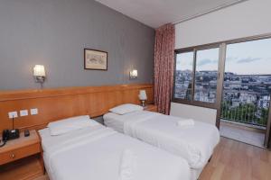 two beds in a hotel room with a large window at Tabar Hotel in Nazareth +71 photos