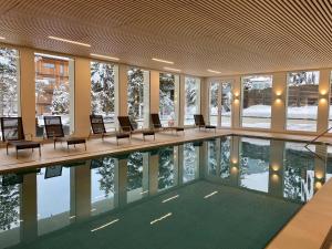 a swimming pool in a building with chairs around it at Residenz by Meierhof in Davos