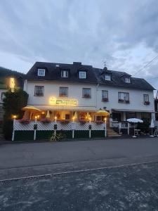 ein großes weißes Gebäude mit einem Restaurant mit gelben Sonnenschirmen in der Unterkunft Gästehaus Hotel zum Weinberg in Burg (an der Mosel)