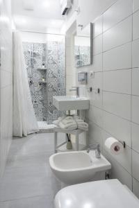 La salle de bains blanche est pourvue d'un lavabo et de toilettes. dans l'établissement Home & Bike Capelli di Venere, à Casaletto Spartano