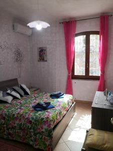 um quarto com uma cama e uma janela com cortinas cor-de-rosa em Il Bronzetto em Gonnesa