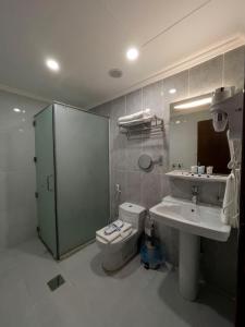 ein Badezimmer mit einem WC, einem Waschbecken und einem Spiegel in der Unterkunft The Palaces Hotel Suites - Wadeen in Chamis Muschait