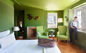 a man standing in a green room with a bed and two chairs at Villa Cascais Boutique Hotel in Cascais