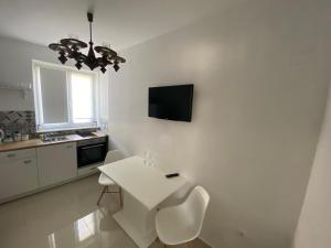 a white kitchen with a white table and a tv on the wall at Apartment Anna in Zadar