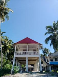 uma casa na praia com palmeiras em Yohanes Guest House Sorake Surf-Nias em Lagudri