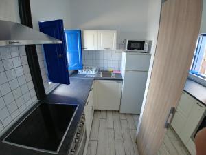 una pequeña cocina con electrodomésticos blancos y armarios azules en Sabbia Suites Serena Studio, en Arrecife
