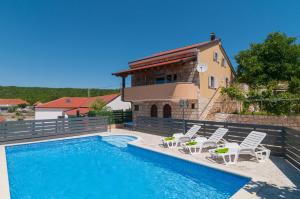 a swimming pool with chairs and a house at Holiday Home Mateovi Dvori in Imotski