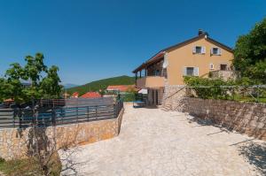 a house with a fence next to a stone wall at Holiday Home Mateovi Dvori in Imotski
