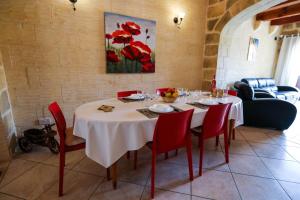 a dining room with a white table and red chairs at Ta'Ruzar Farmhouse in Xagħra