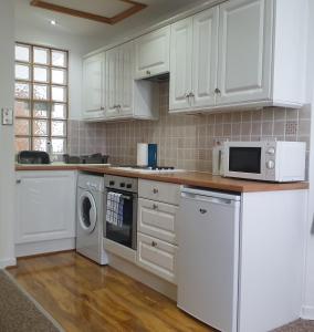 kuchnia z białymi szafkami, pralką i suszarką w obiekcie A Beautiful Apartment with Stunning Sea Views & Private Balcony w Bournemouth