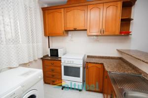a kitchen with wooden cabinets and a white stove top oven at Edificio Esmeralda in Peniscola