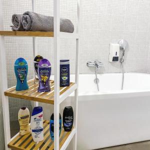 a shelf with products on it next to a bath tub at 4Rooms in Maribor