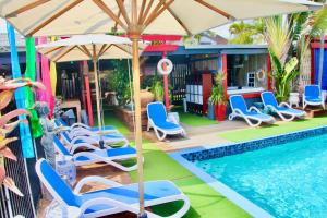 a pool with chairs and umbrellas in it at Hideaway Noosa Men Only Beach Resort in Peregian Beach