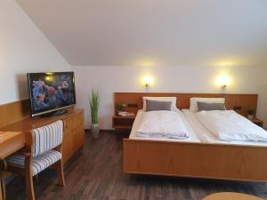a bedroom with a bed and a desk and a tv at Kurhotel Anders in Bad Füssing