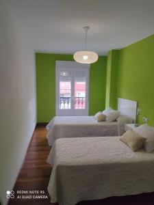 a room with four beds with green walls and a chandelier at Apartamento Paula in Cee