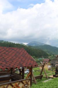uma casa com um telhado vermelho com montanhas ao fundo em У Василини em Yablunytsya