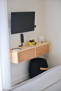 a desk with a television on a wall with a chair at Princess Mare Hotel - Adults Only in Naxos Chora