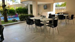 comedor con mesa blanca y sillas negras en Flat Prive das Thermas II - R3 Caldas, en Caldas Novas