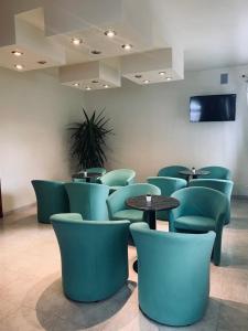 poczekalnia z zielonymi krzesłami i stołami w obiekcie Hotel Al Capitano w Caorle