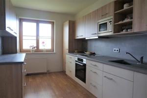 a kitchen with white cabinets and a sink and a window at Maierlhof in Aich
