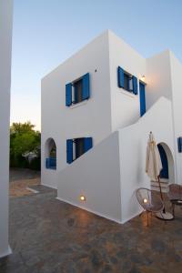 a white building with blue windows and a chair at Kanellis Studios in Avlemonas
