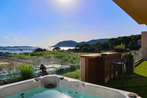 uma banheira de hidromassagem numa varanda com vista para a água em CALADEA Locations de Vacances 5 étoiles, piscine chauffée em Porto-Vecchio