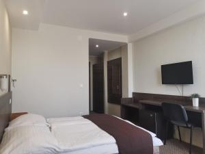 a bedroom with a bed and a desk and a television at Hotel Tagore in Balatonfüred