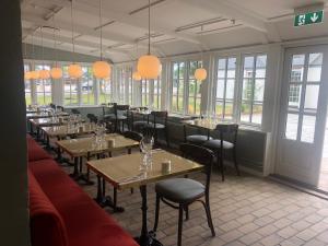 a dining room with tables and chairs and windows at Hotel Nørrevang in Bøtø By