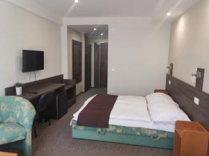 Hotel Tagore في بالاتونفوريد: غرفة نوم بسرير ومكتب وجهاز كمبيوتر