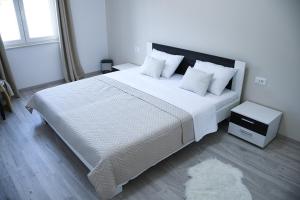 1 dormitorio con 1 cama grande con sábanas y almohadas blancas en Apartment Light en Stobreč