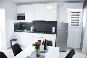 una cocina con armarios blancos y una mesa con flores. en Apartment Light en Stobreč