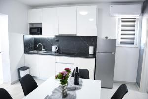 a kitchen with white cabinets and a table with flowers on it at Apartment Light in Stobreč