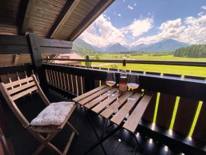 een houten tafel met twee glazen wijn op een balkon bij Haus am Gaisalpbach in Oberstdorf