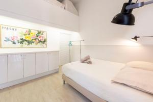 カンヌにある1 bedroom apartment with 1 mezzanine top location in the heart of Cannesの白いベッドルーム(ベッド1台付)が備わります。壁には絵画が飾られています。