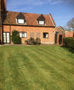 a brick house with a large lawn in front of it at Dairy Cottage in Cockley Cley