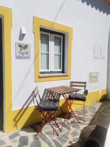 a table and two chairs next to a building at Chão da Velha - Casas de Campo in Nisa