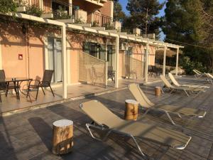 eine Gruppe von Stühlen und Tischen auf einer Terrasse in der Unterkunft Despina Studios and Apartments in Lassi