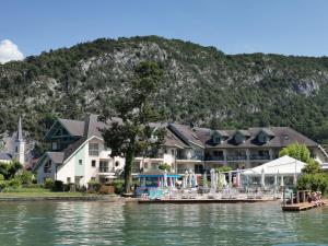 un complexe sur l'eau avec une montagne en arrière-plan dans l'établissement Lac Annecy plage privée, Duplex Baie des voiles, à Duingt