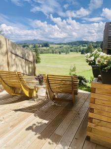 dois bancos num deque com vista para um campo em ALPEN WOHLFÜHLQUARTIER em Bayersoien