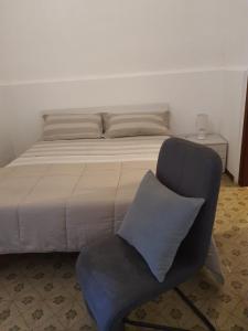 - une chambre avec un lit, une chaise et un oreiller dans l'établissement Maison Mafalda, à Surbo