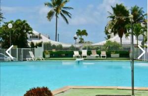 a large swimming pool with chairs and palm trees at Rêve bleu in Le Gosier