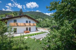 a white house with a wooden balcony on a hill at Der Söllhof in Bressanone