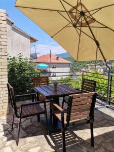 a wooden table with two chairs and an umbrella at Trpejca Holiday Home in Trpejca