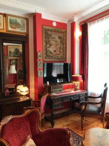 a living room with a piano and a red wall at Dwór Barocco in Reszel